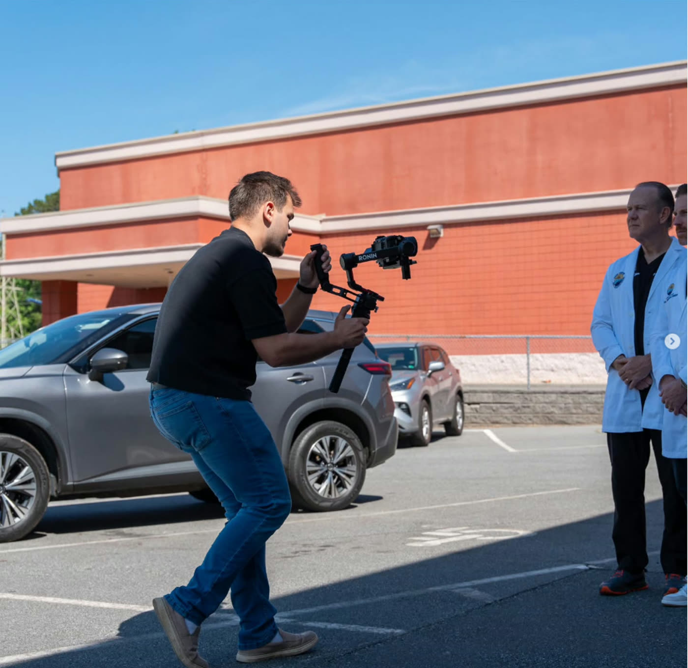 Videographer shooting handheld on a gimbal in a parking lot